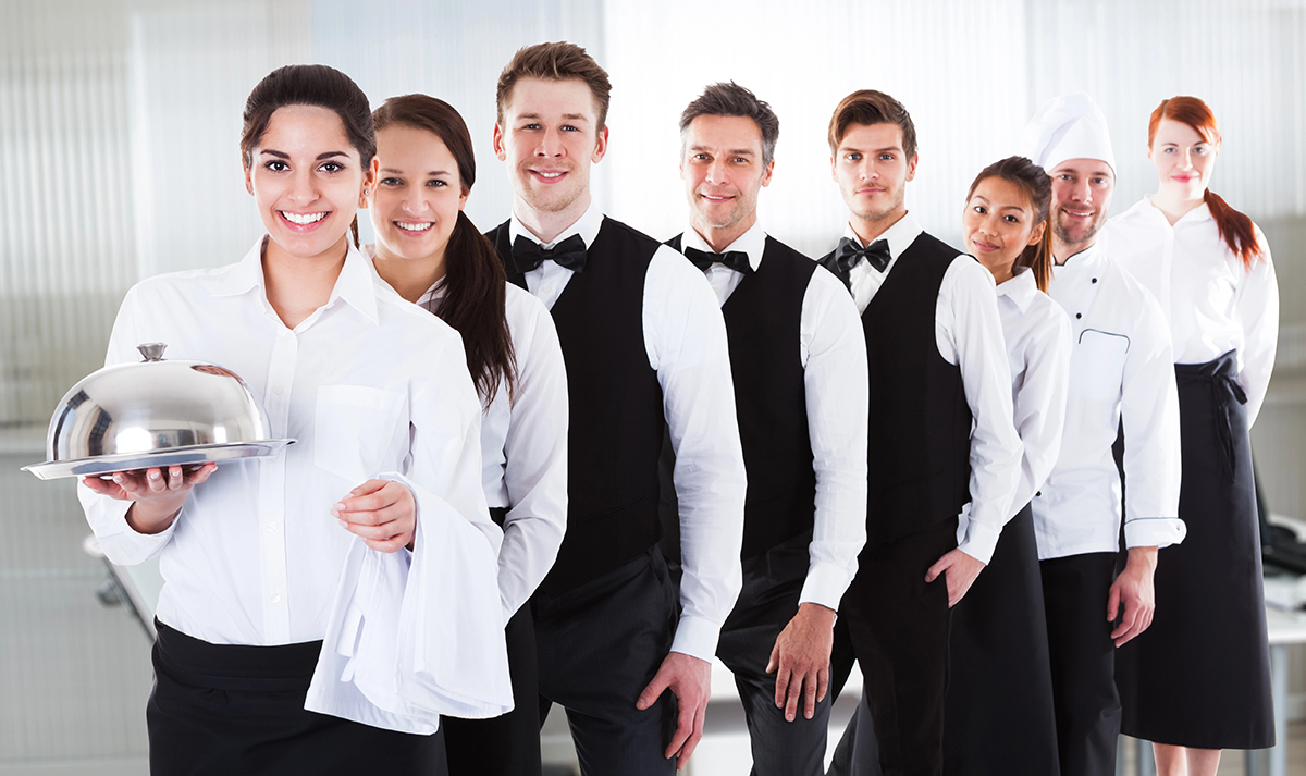 Junge Kellner und Kellnerinnen zusammen mit dem Koch